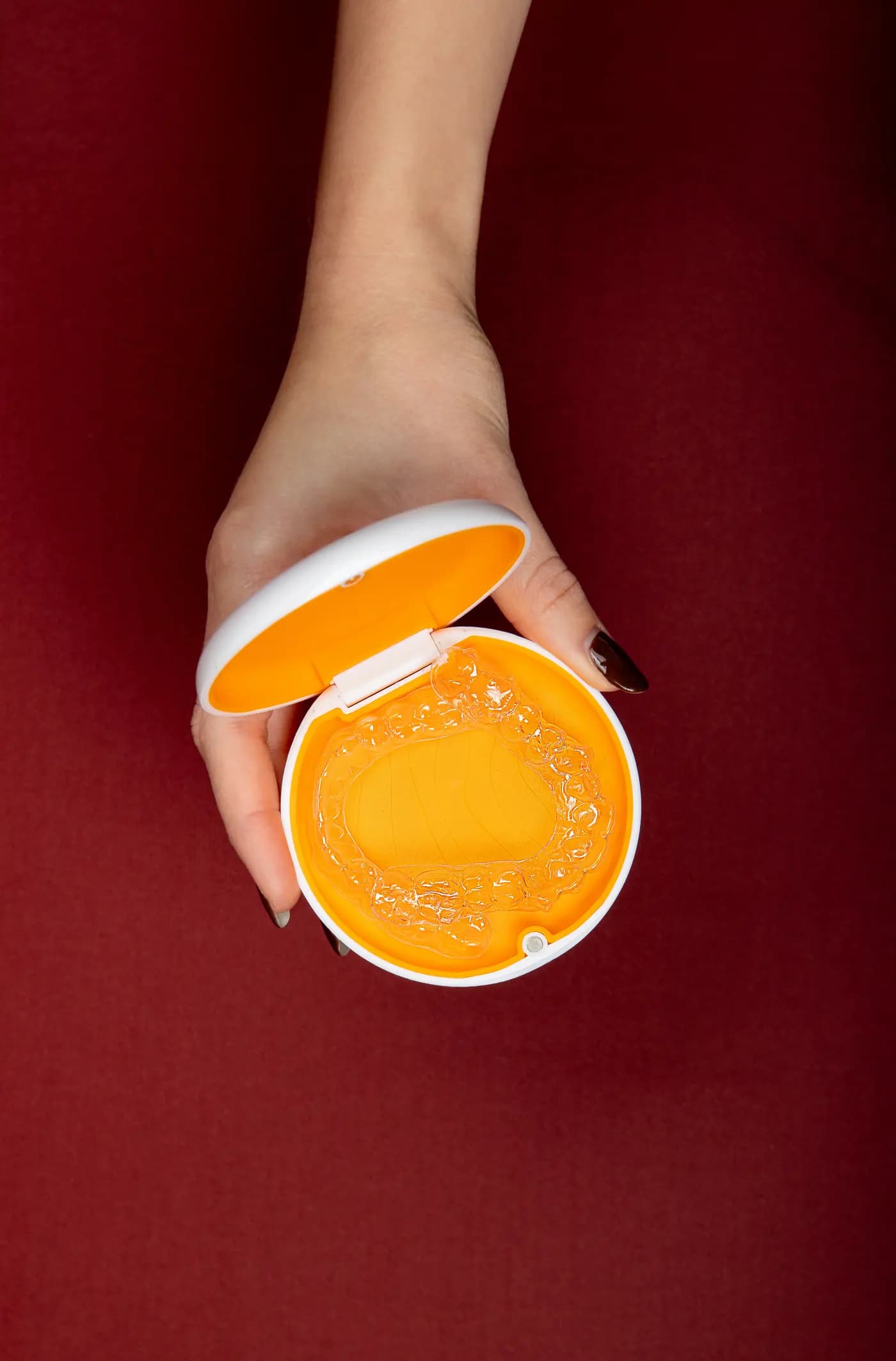 A hand holding an open Mia Aligners case