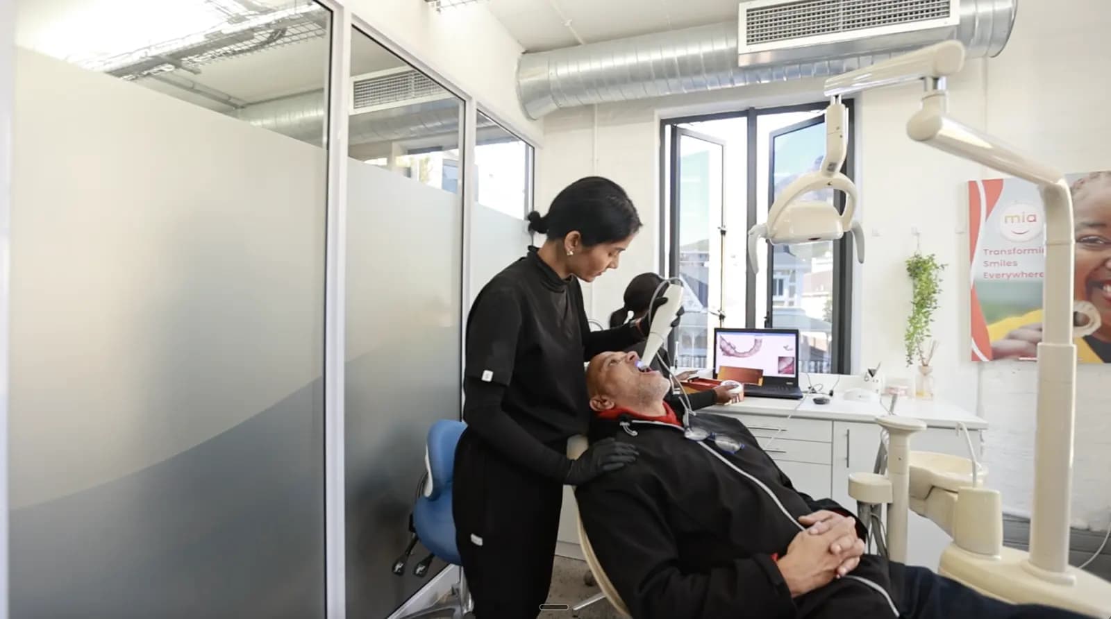 Female dentist in black scanning a male patient