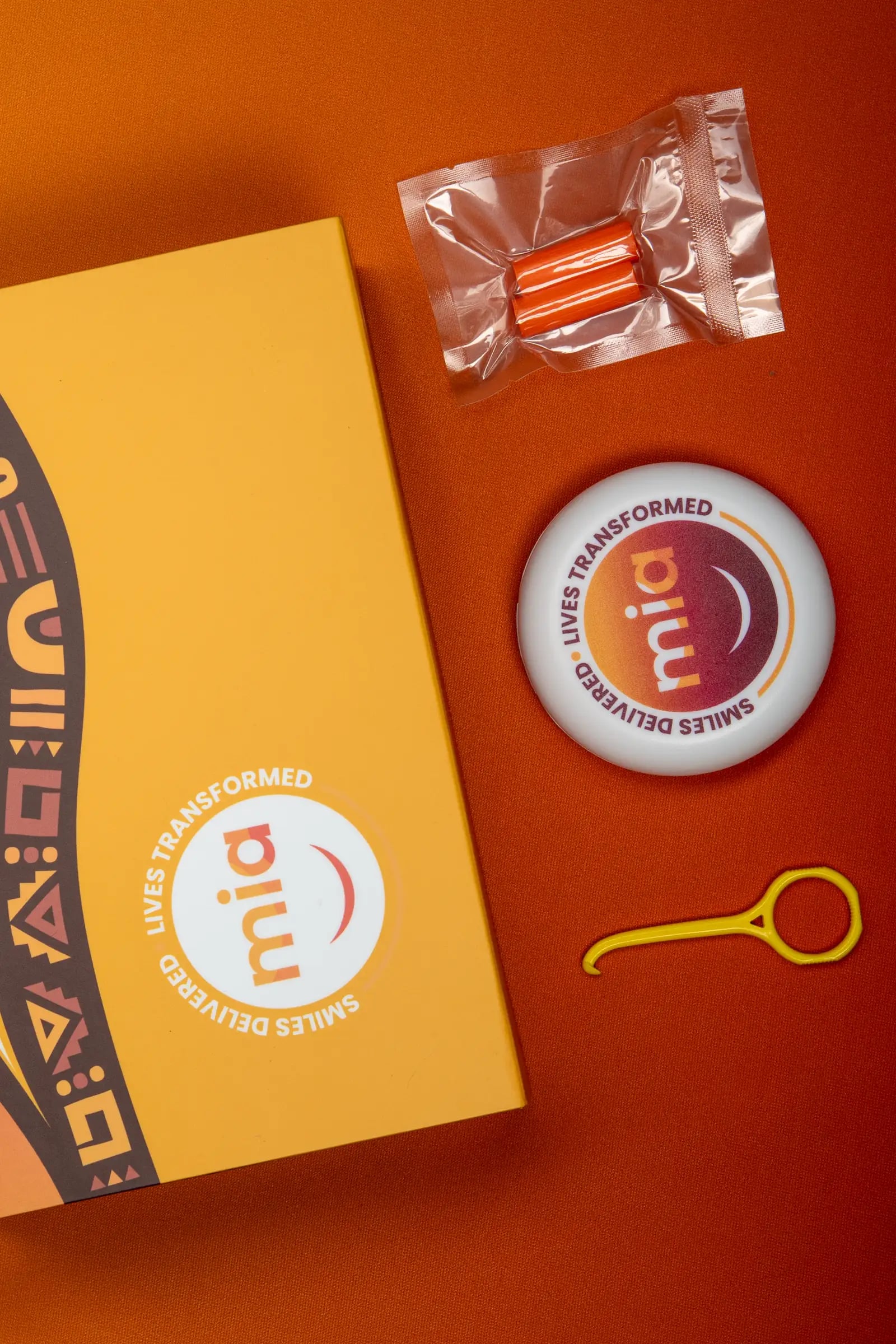 Orange flat-lay of a Mia box, case, chewies and hook