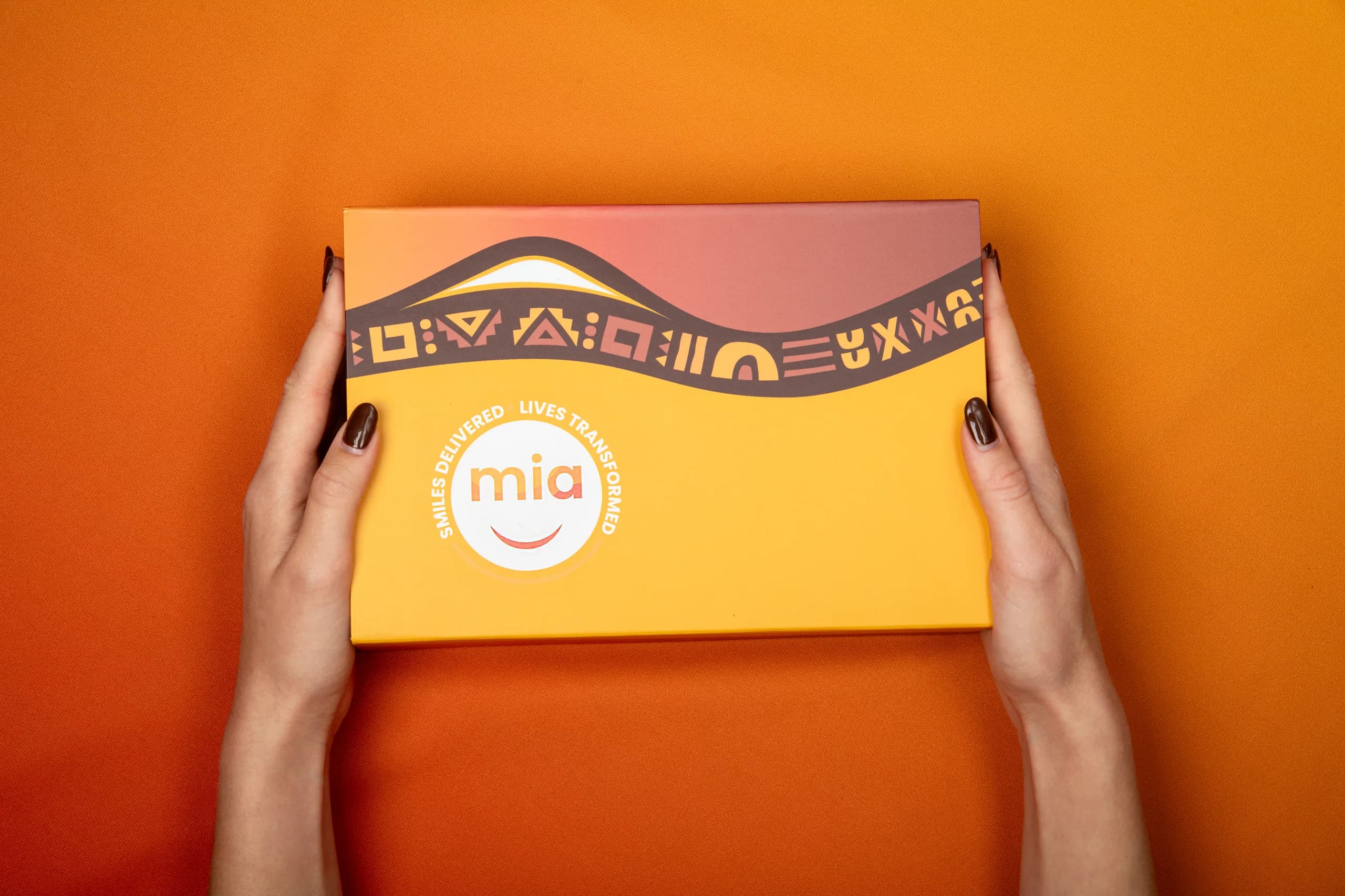 Hands holding an orange Mia aligner box